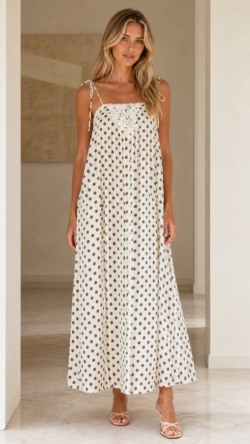 Front view of woman wearing white polka dot maxi dress with tie straps