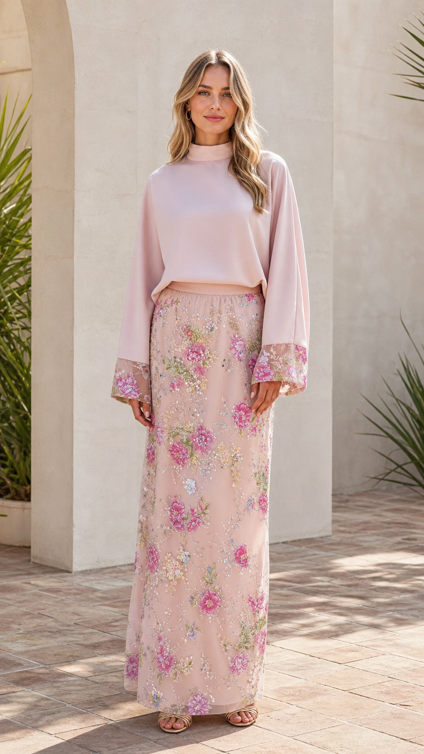 Model wearing pink mock neck top and floral embroidered maxi skirt, full length front view