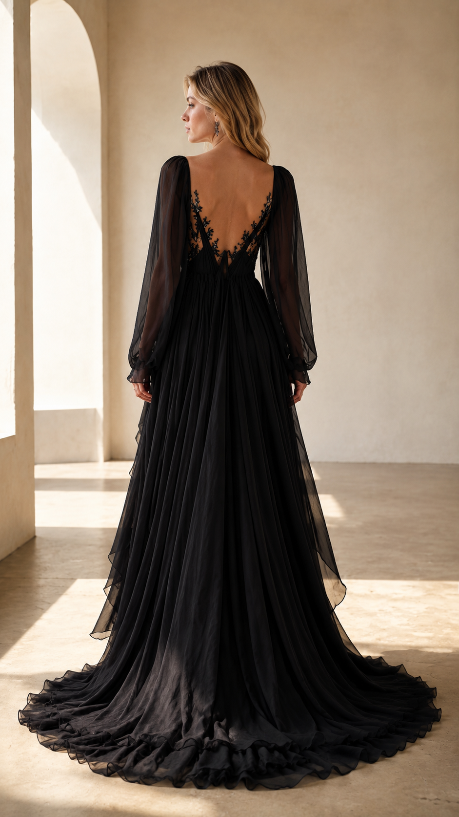 Back view of black sheer sleeve pleated maxi gown with low back and sweeping hem