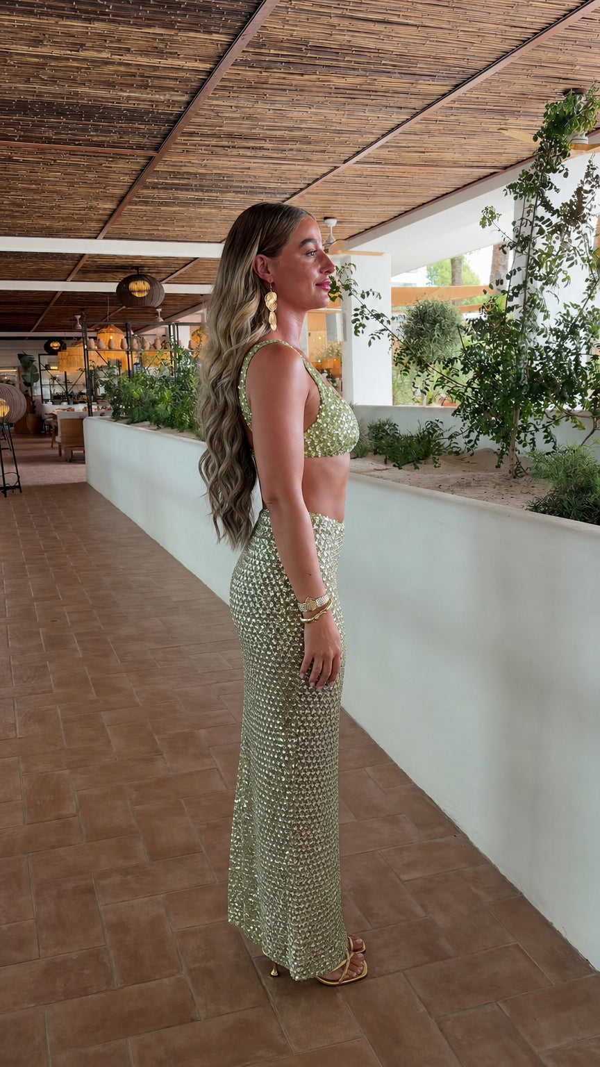 Side profile of model in sage green sequin crop top and maxi skirt