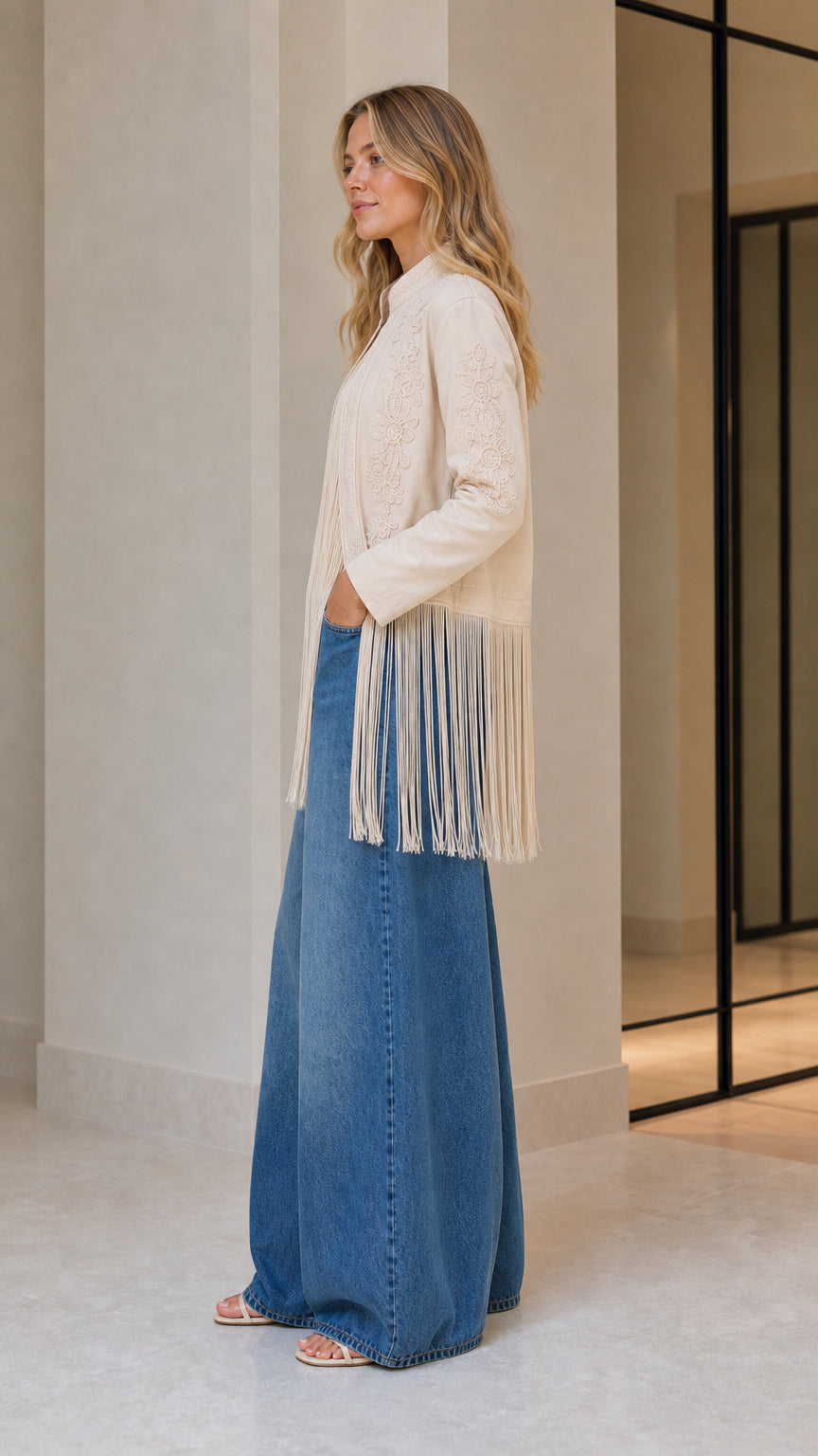 Model wearing beige embroidered fringe jacket, side view
