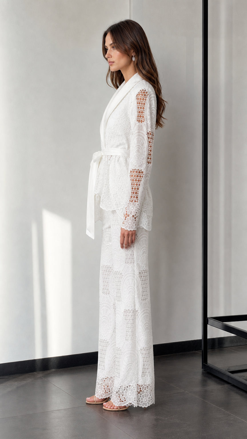 Side profile of woman in white lace pantsuit with tie belt
