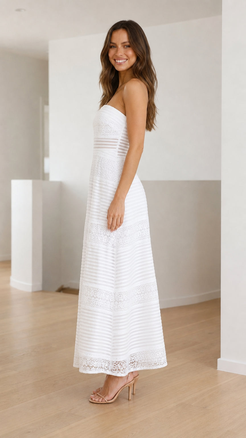 Side profile view of white strapless lace maxi dress