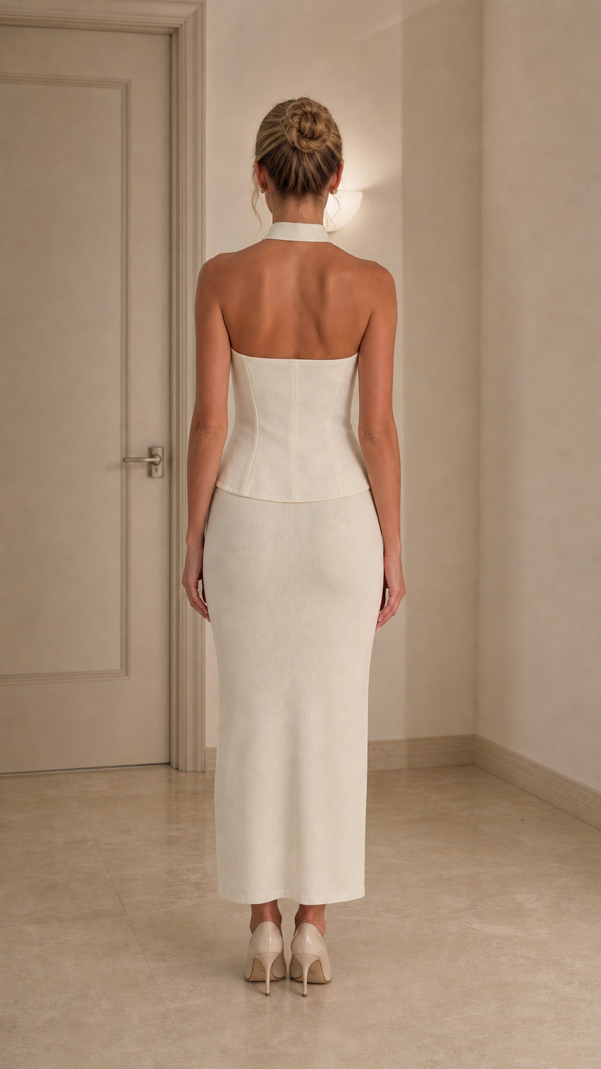 Back view of model wearing ivory halter top and midi skirt