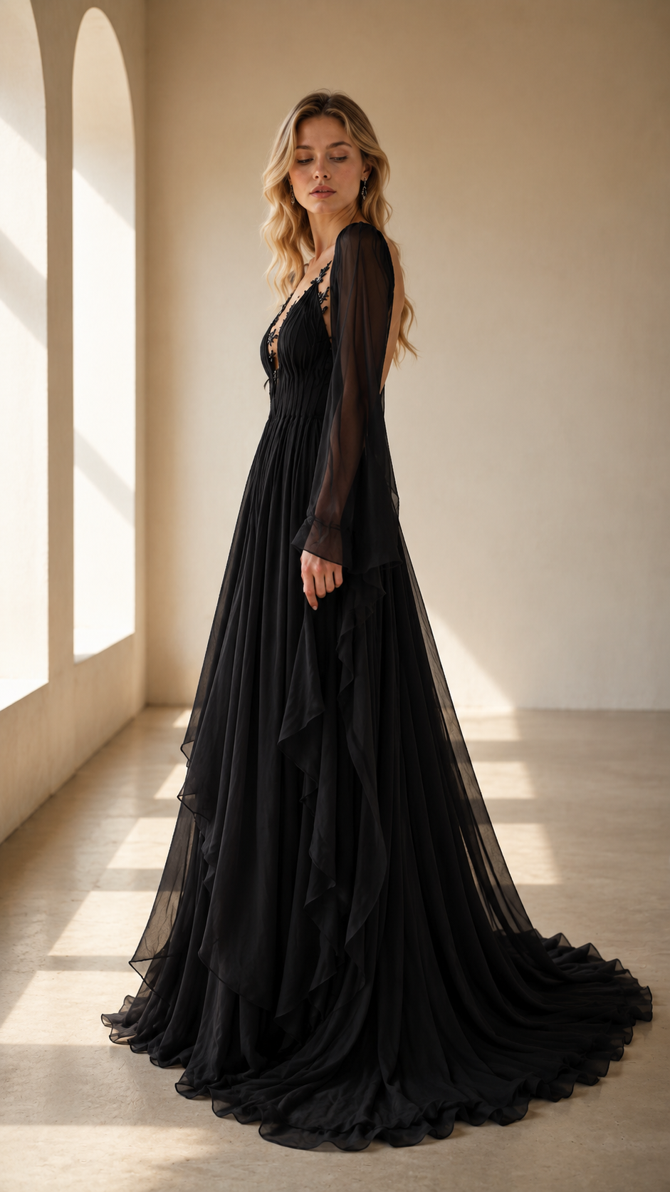 Side view of black lace appliqué maxi gown with sheer long sleeves and flowing skirt