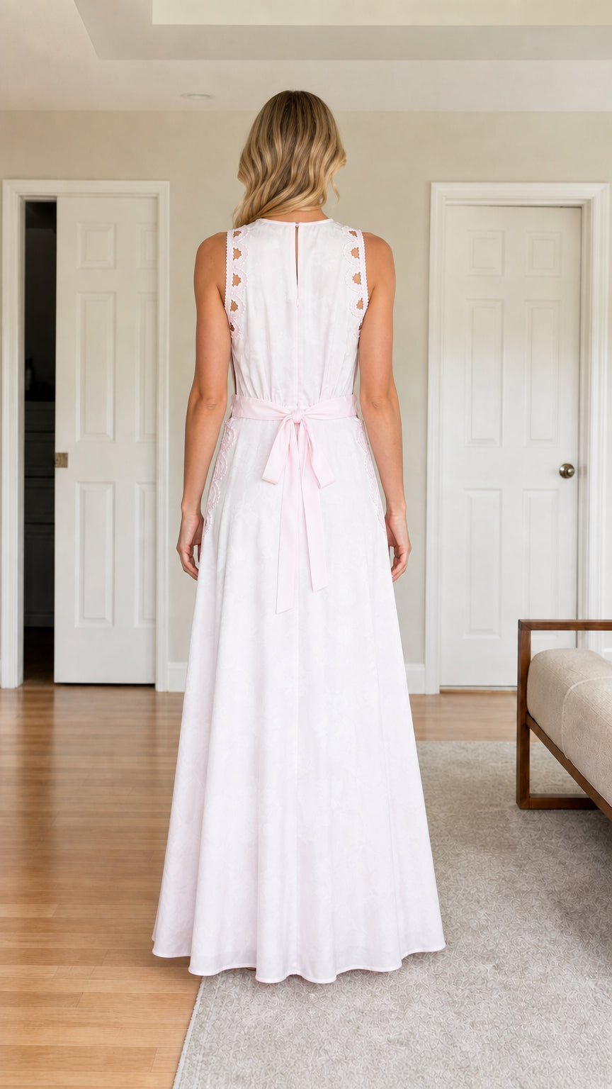 Back view of woman wearing white cutout maxi dress showing bow detail