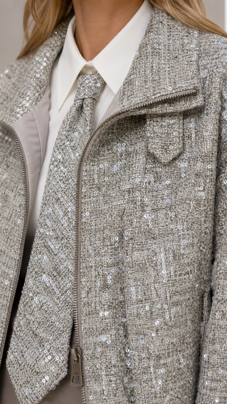 Close-up detail of grey tweed fabric with subtle sequins and zipper