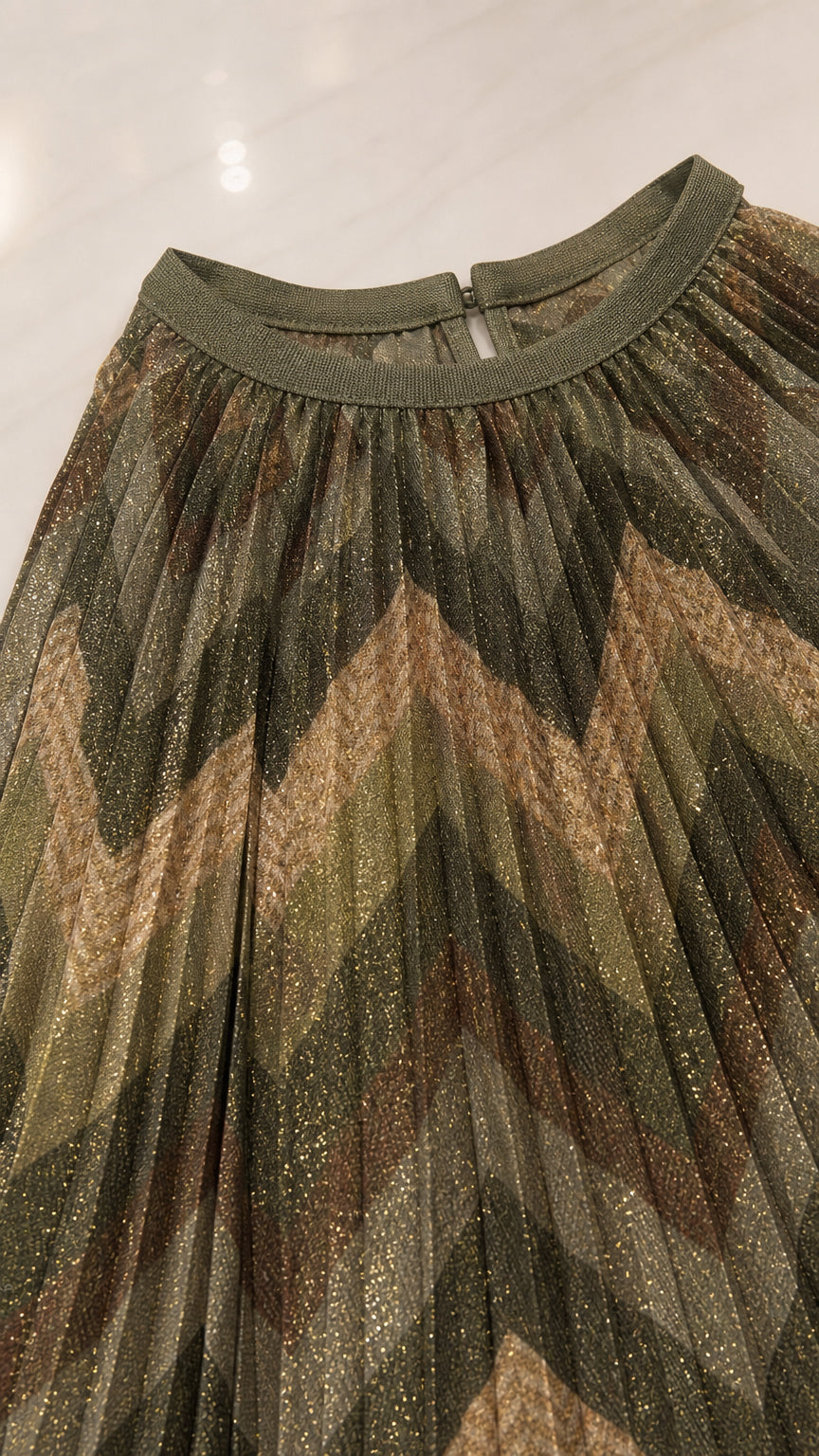 Close-up detail of green metallic chevron pleated fabric and neckline