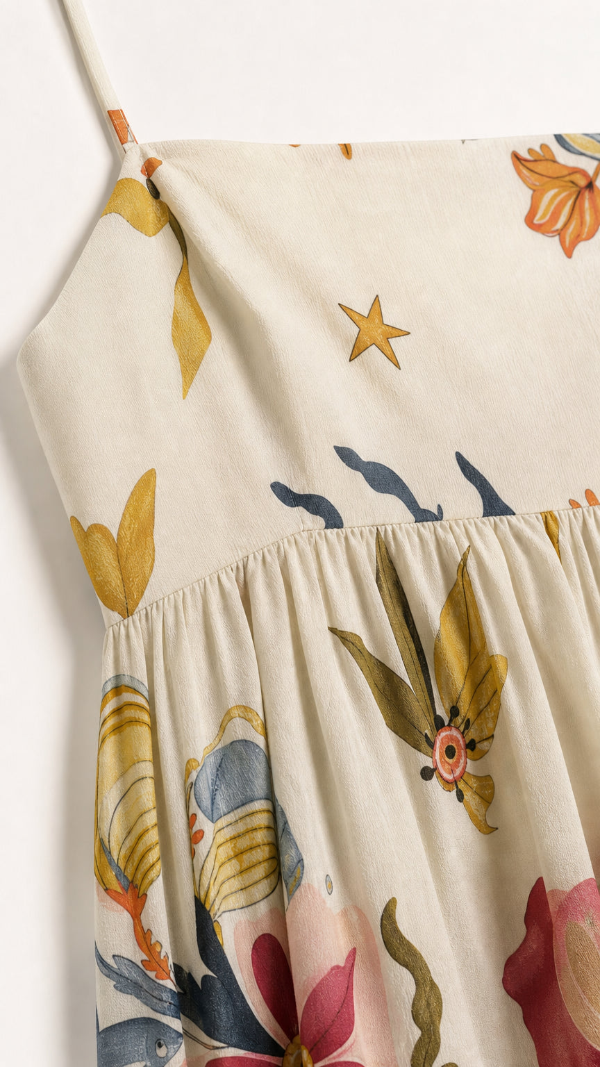 Close-up detail of fabric, print, and straps on cream dress