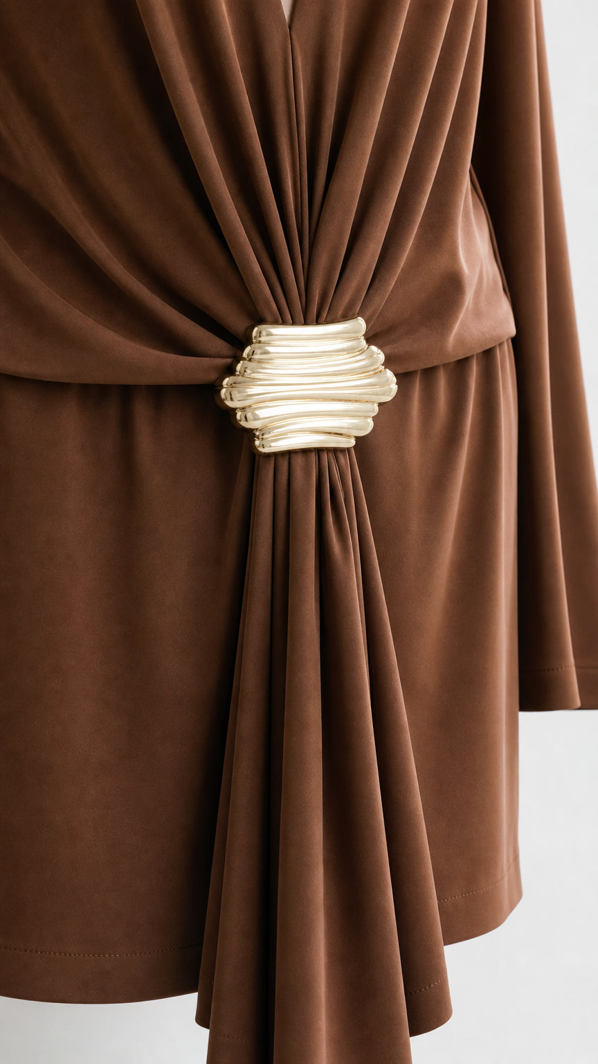Close-up of sculptural gold-tone waist buckle and draping