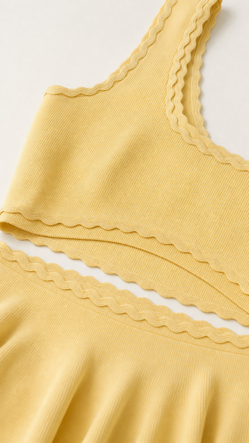 Close-up of butter yellow ribbed knit fabric and scalloped trim