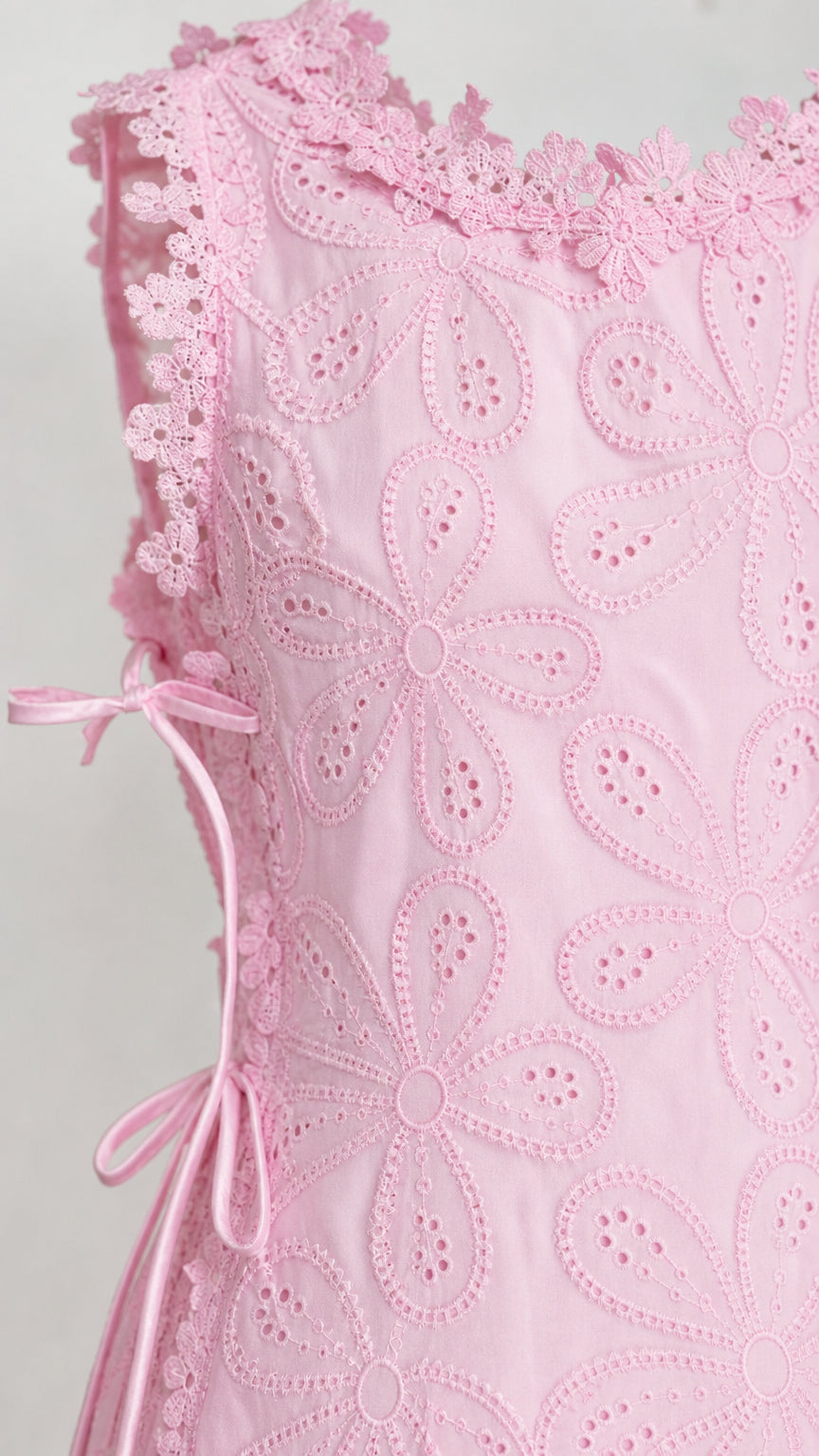 Close-up detail of pink floral eyelet fabric and side tie