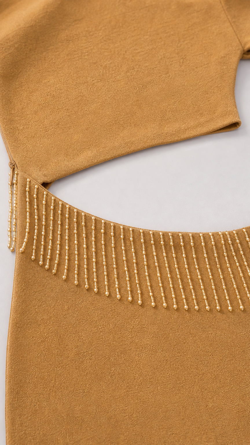 Close-up detail of the waist cutout and beaded fringe trim on the dress