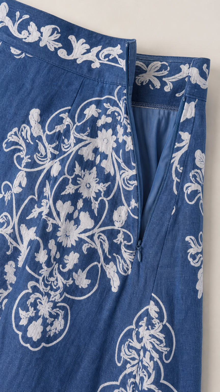 Close-up of blue skirt fabric showing side zipper and botanical pattern