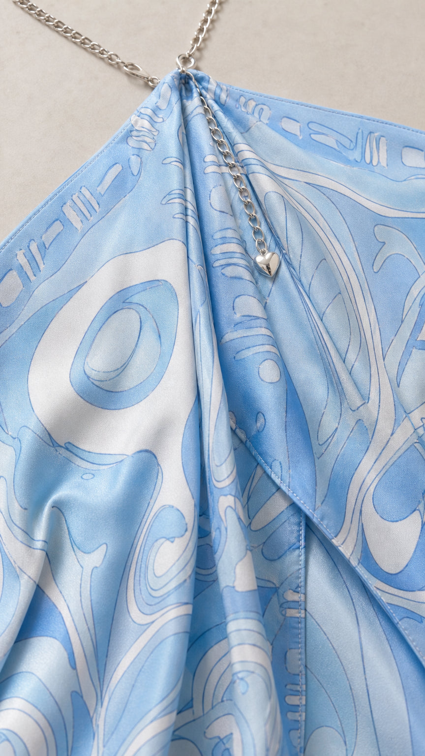 Close-up of sky blue abstract print fabric and metallic chain halter detail