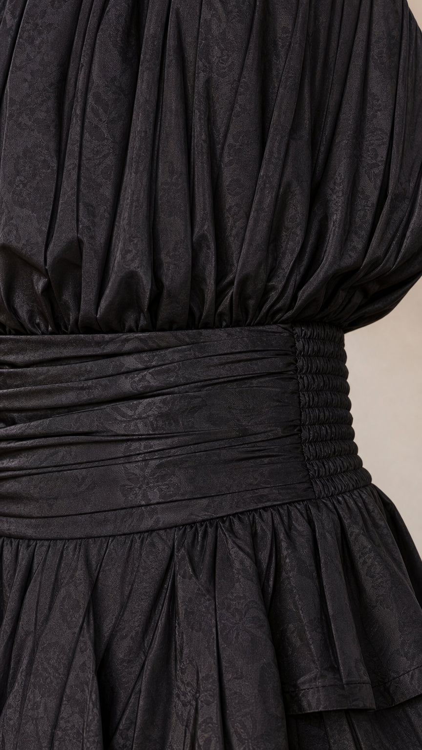 Close-up detail of smocked waist and textured fabric on black romper
