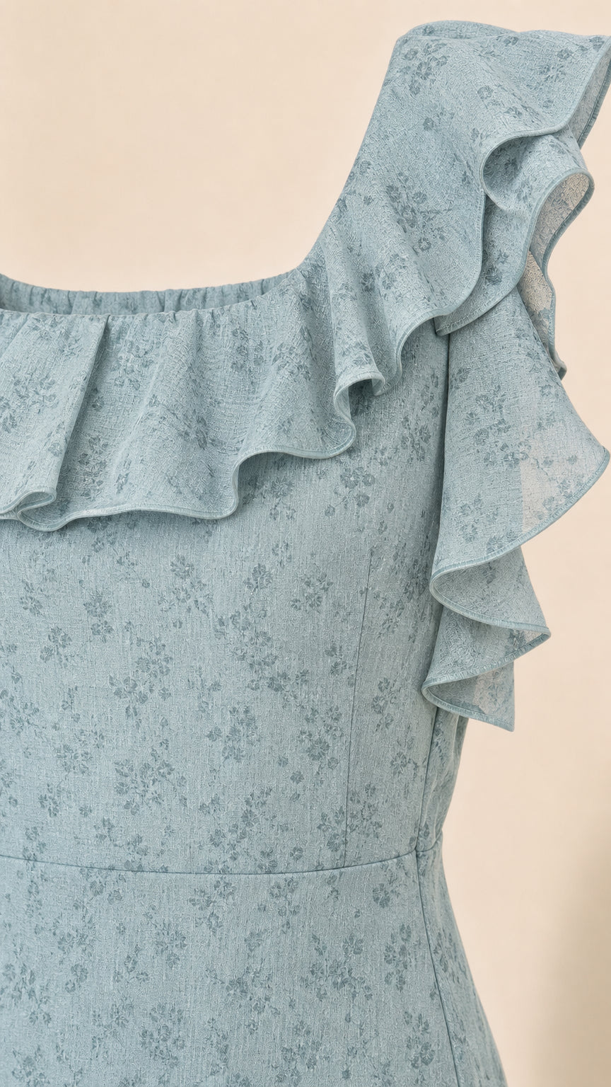 Close-up detail of ruffled shoulder and neckline on blue dress