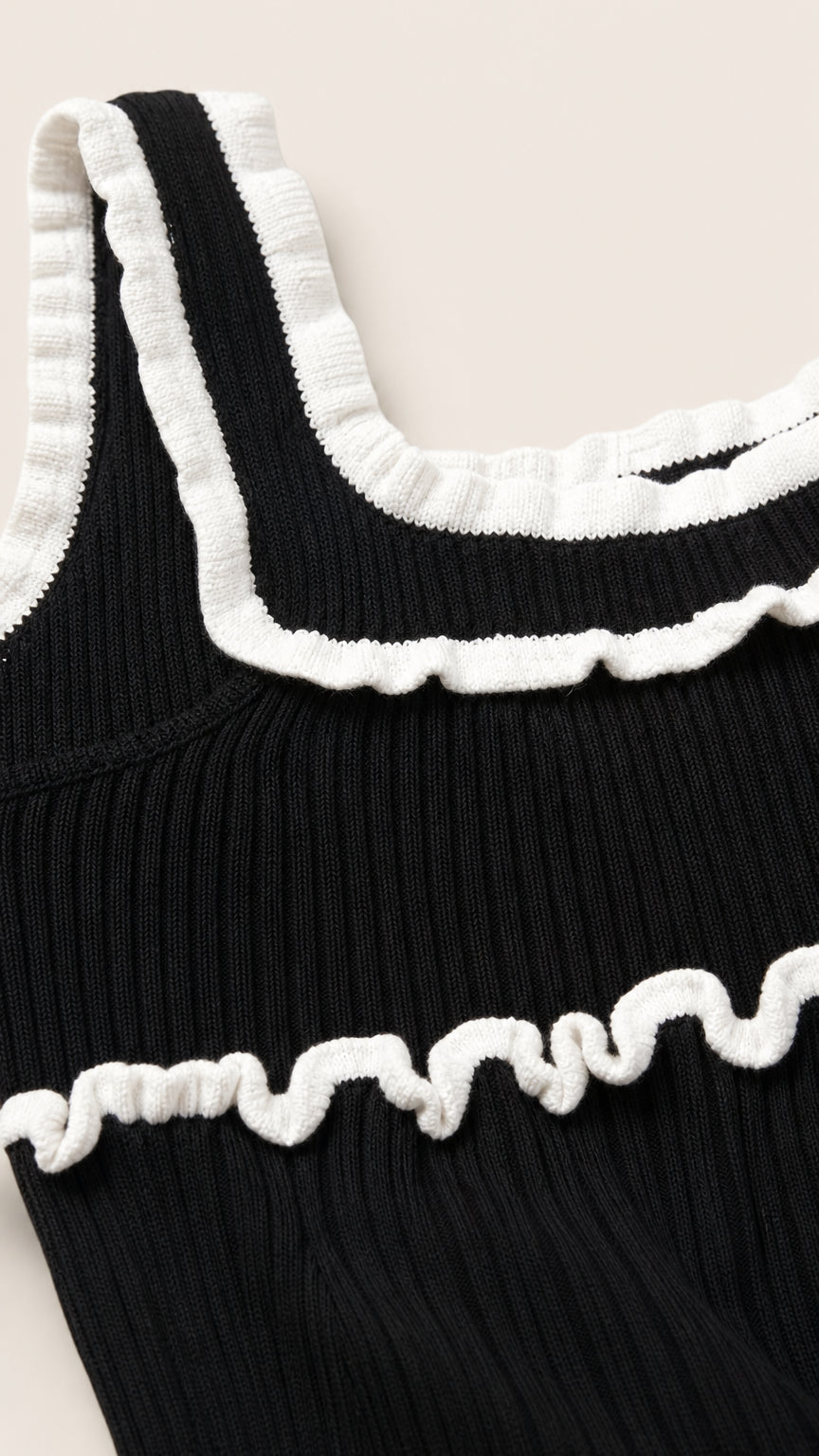 Close-up detail of white lettuce ruffles on black knit top