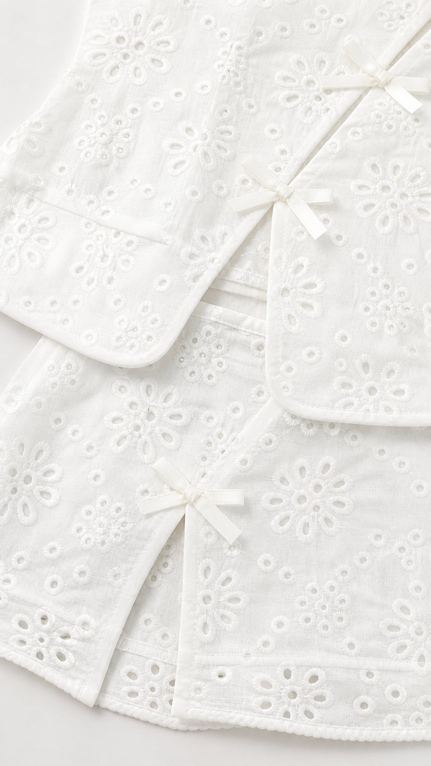 Close-up of white eyelet fabric and bow details