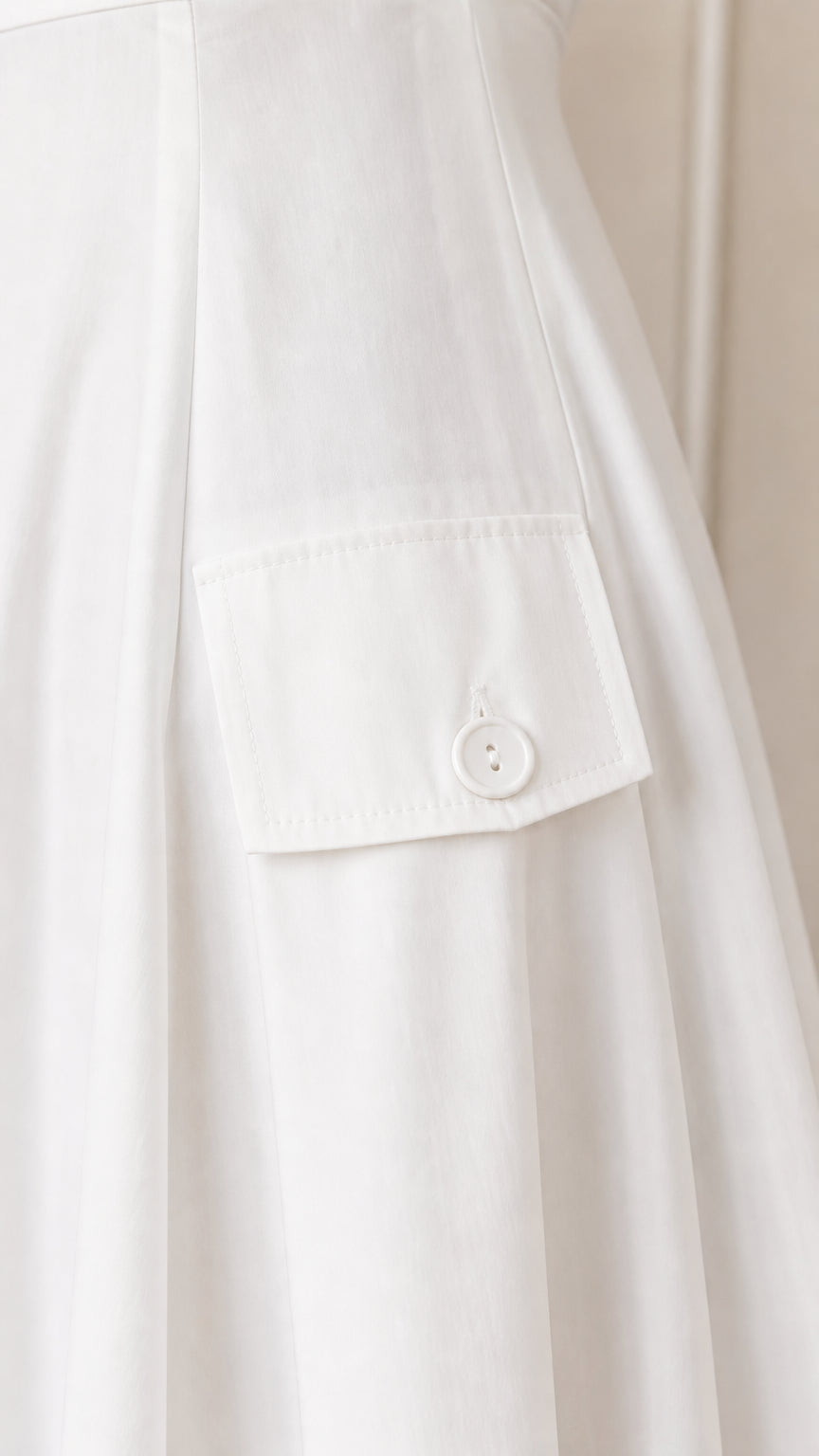 Close-up detail of pocket and button on white dress