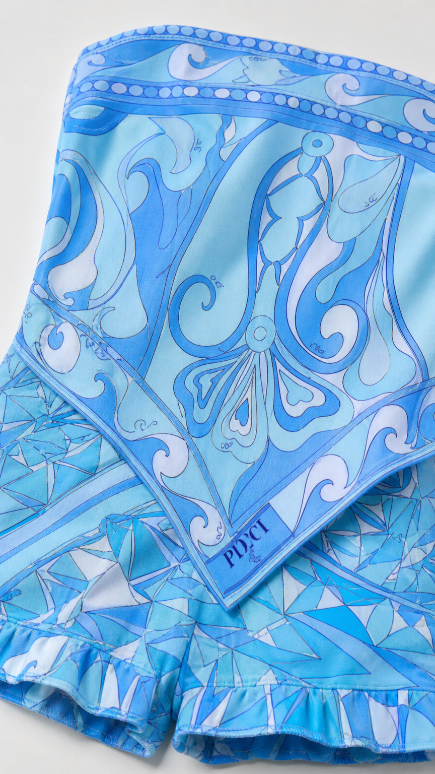 Close-up detail of the blue geometric scarf pattern and ruffle hem