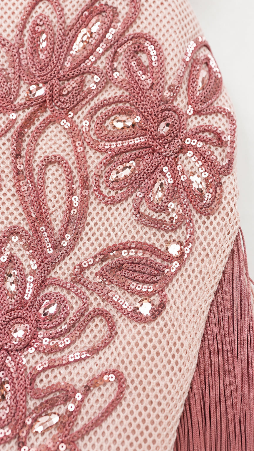 Close-up detail of floral embroidery and sequins on mesh fabric