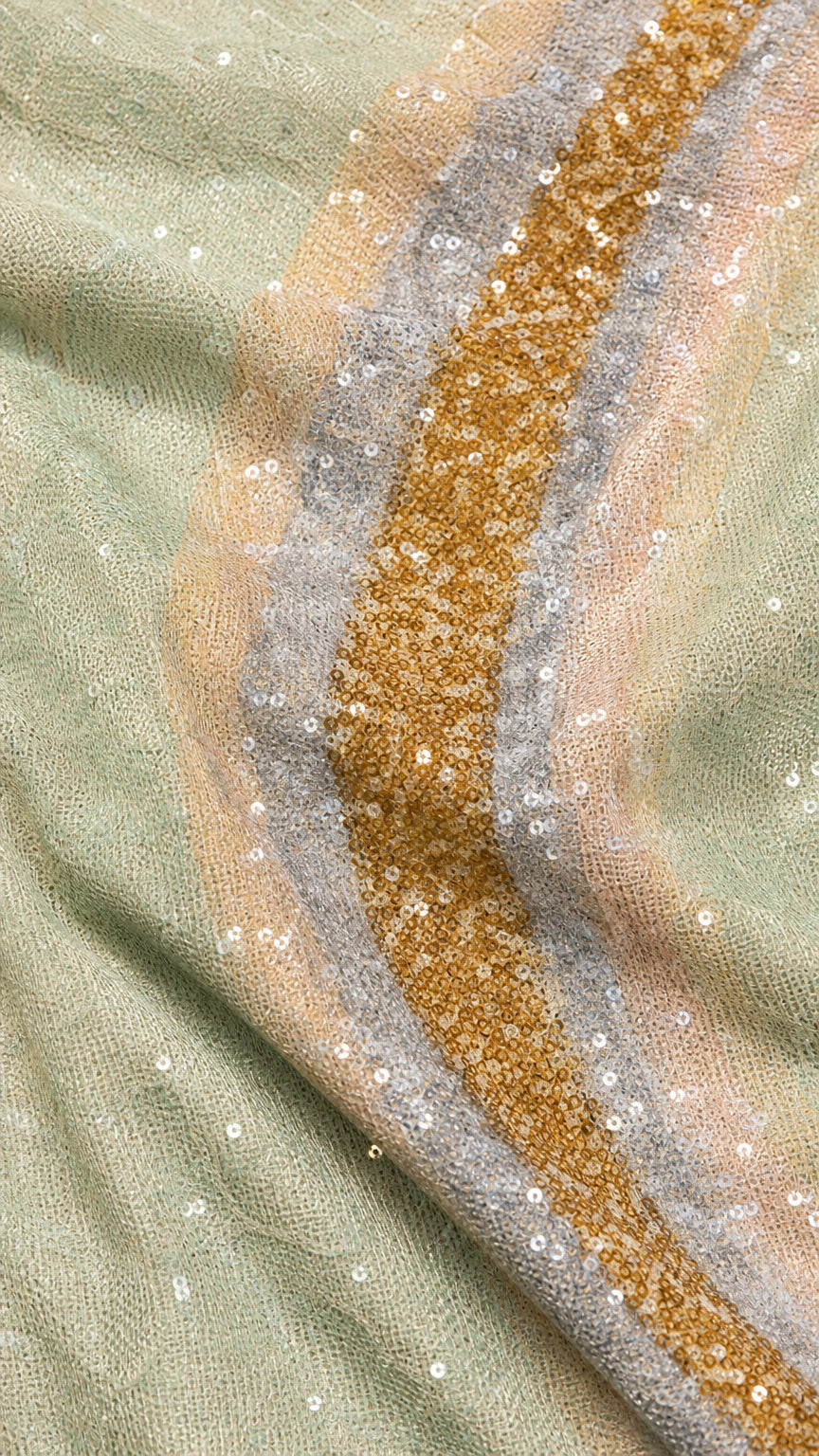 Close-up of gold, silver, and mint sequin wave fabric texture
