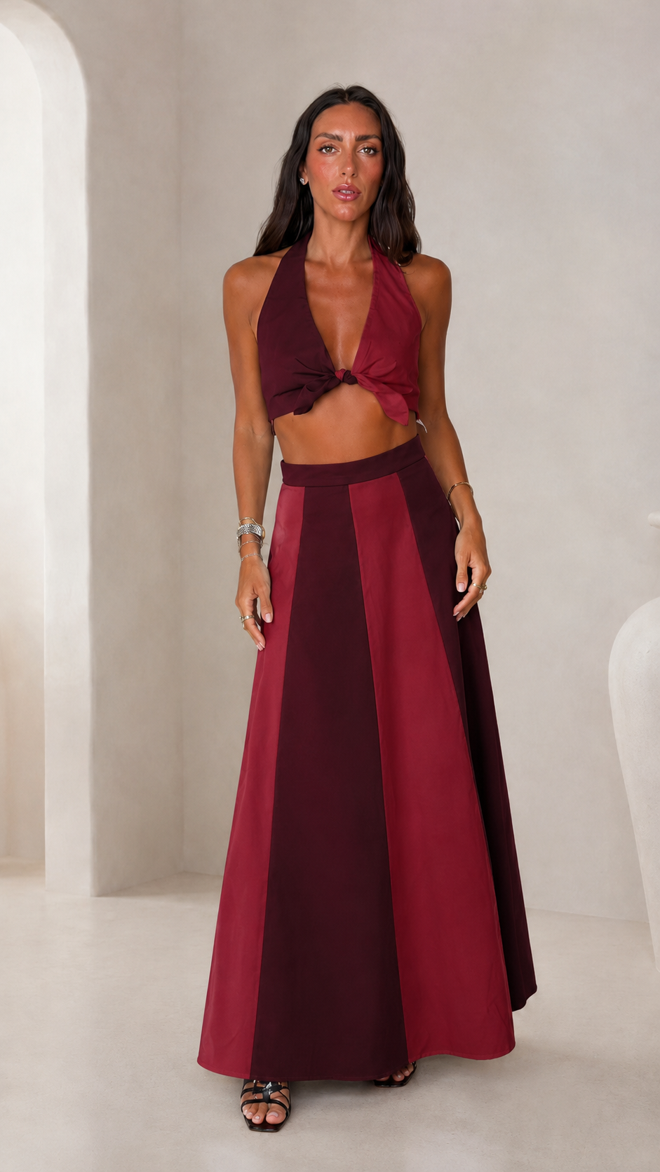 Front view of burgundy halter crop top and color block maxi skirt set