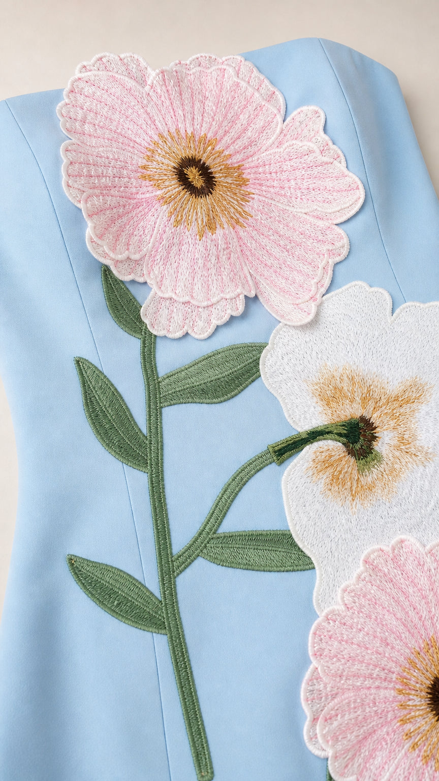 Close-up detail of 3D floral embroidery on light blue dress