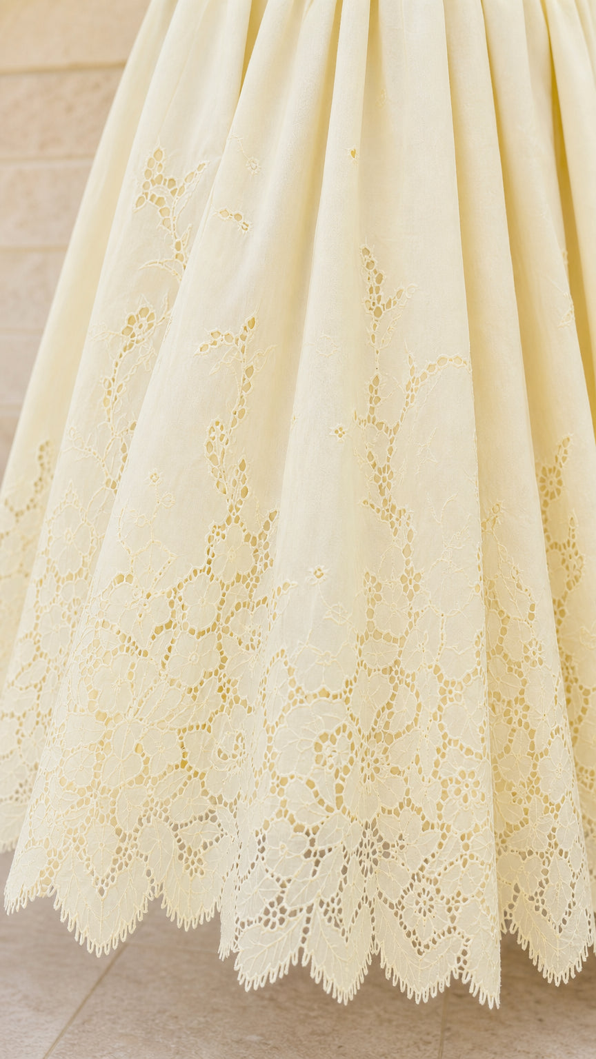 Close-up detail of lace embroidery on yellow dress hem