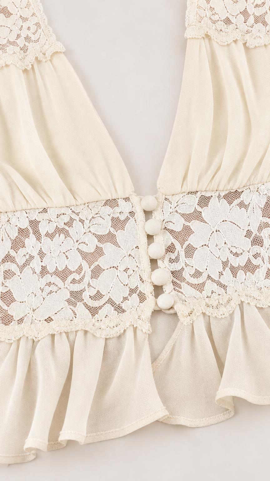 Close-up of lace trim and button details on cream crop top