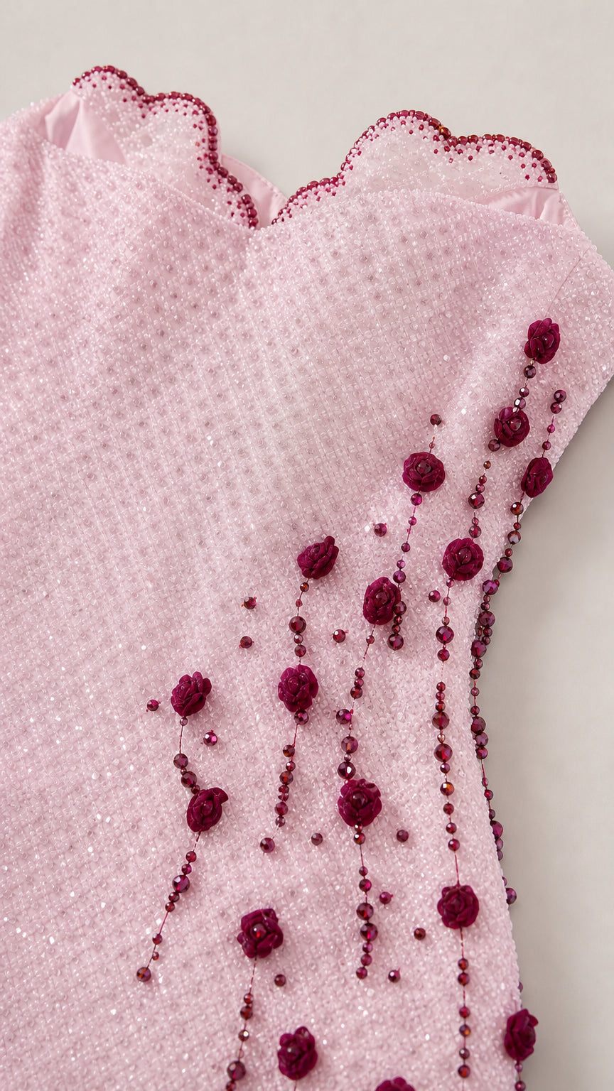 Close up of scalloped neckline and cascading beaded floral details on pink dress