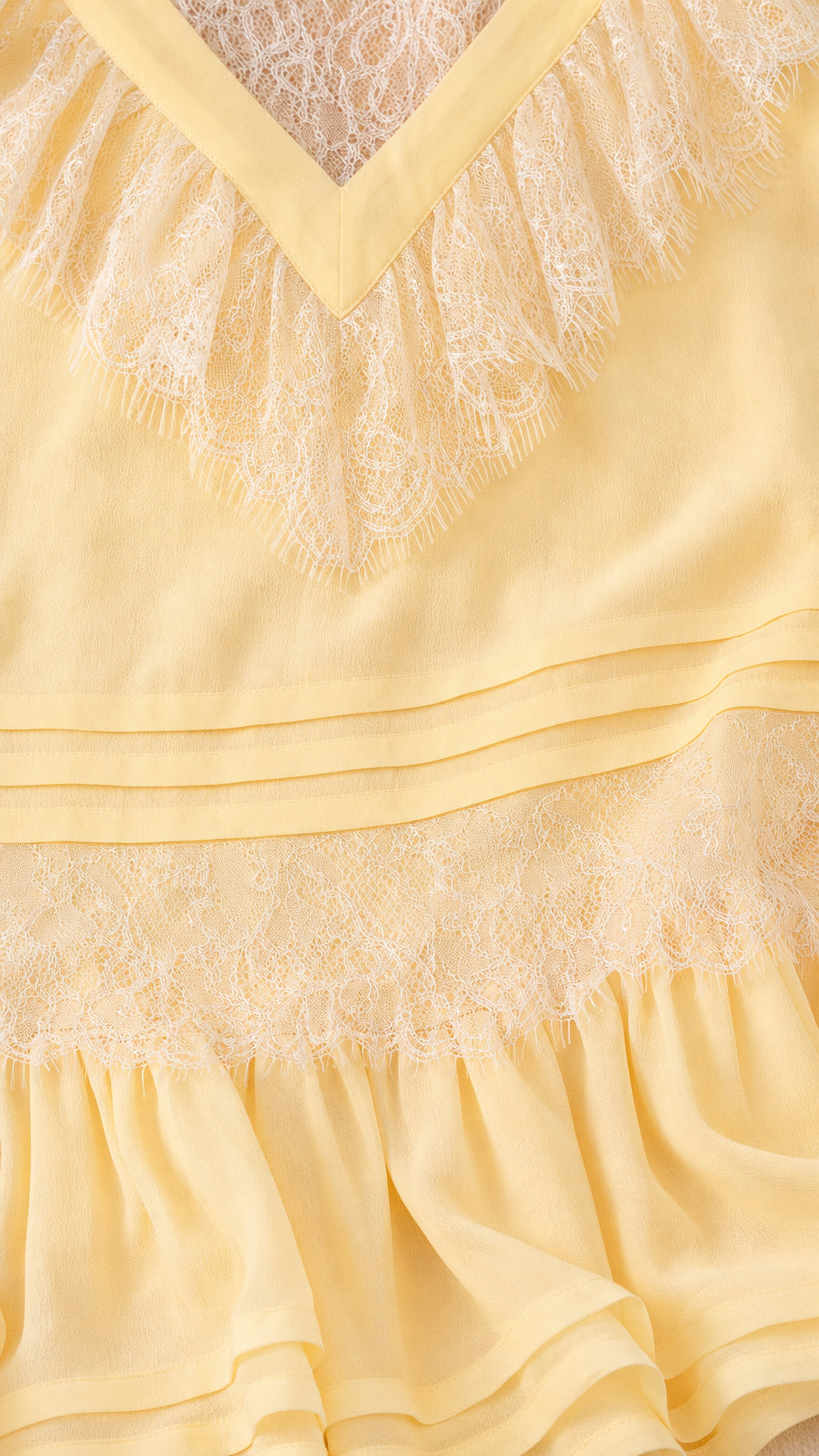 Close-up detail of V-neck ruffles and lace on yellow dress