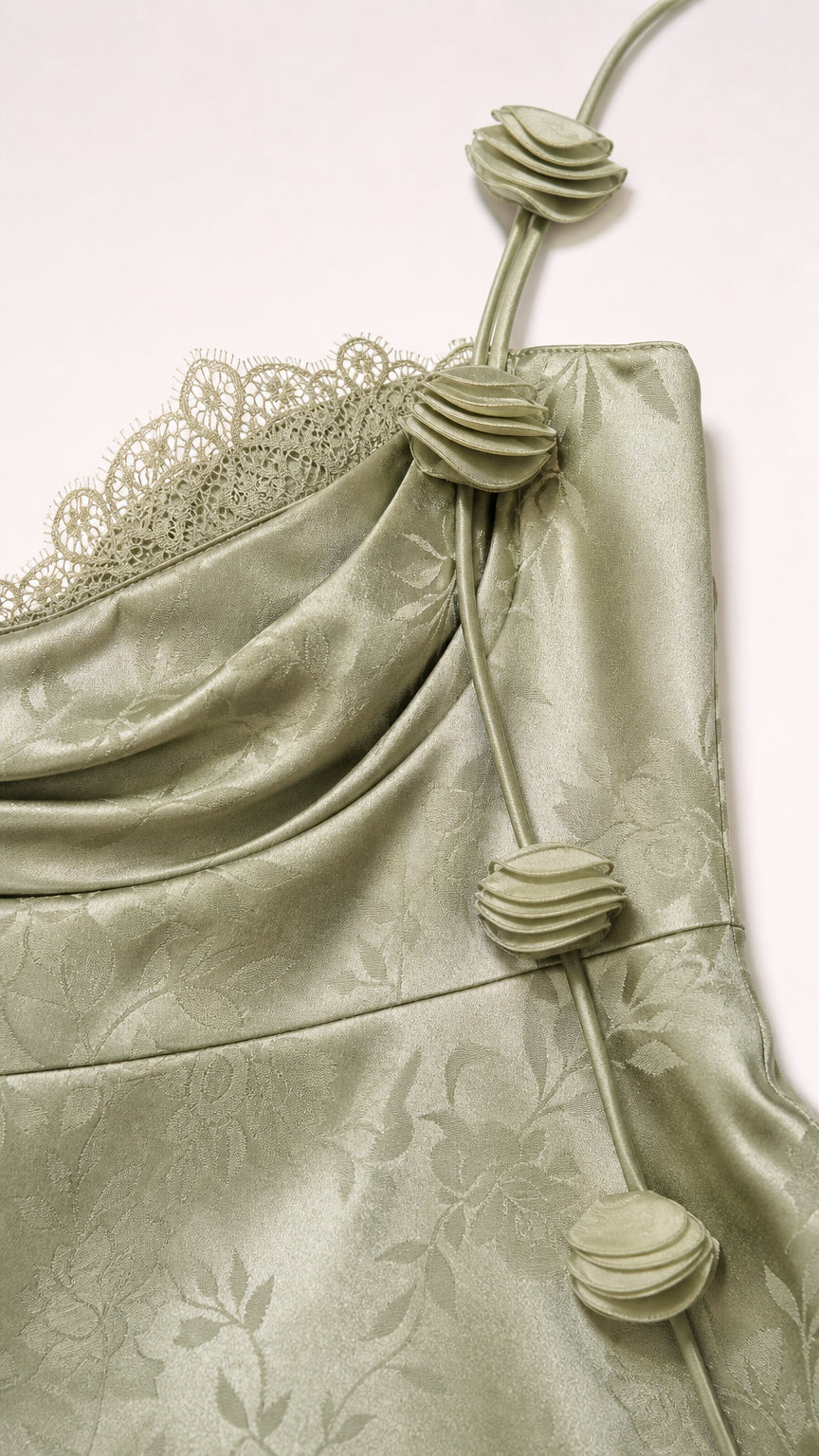 Close-up of rosette strap and lace detail on sage green dress