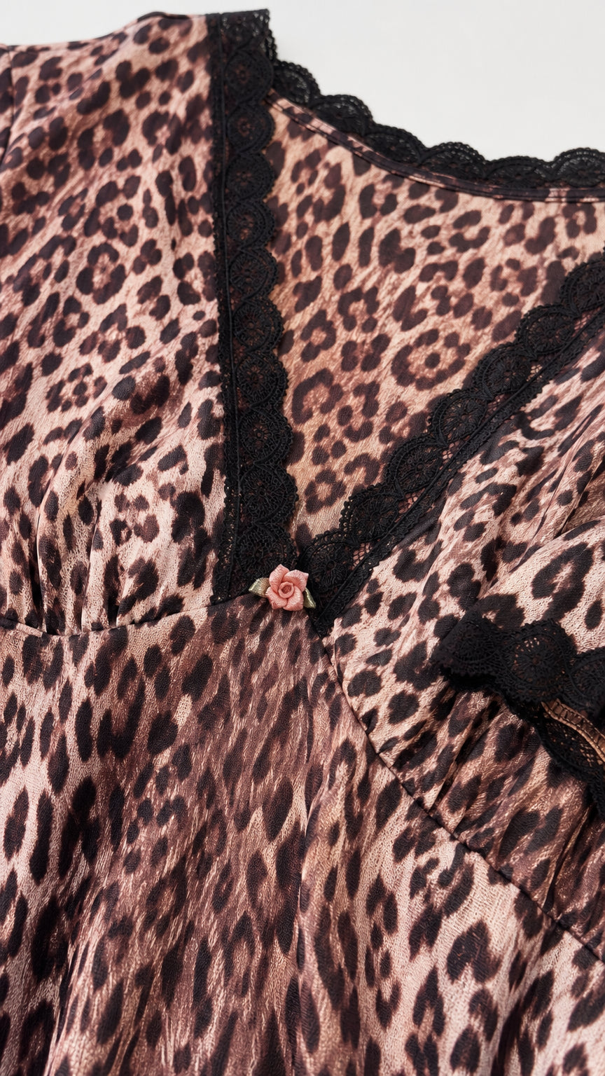 Close-up detail of V-neckline, black lace trim, and rose applique