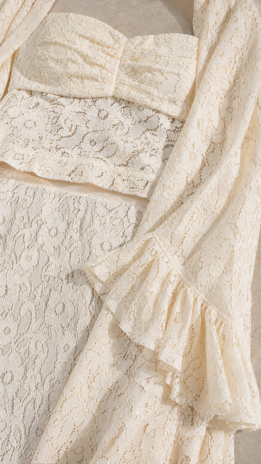 Close-up detail of cream lace fabric texture, crop top, and ruffled sleeve