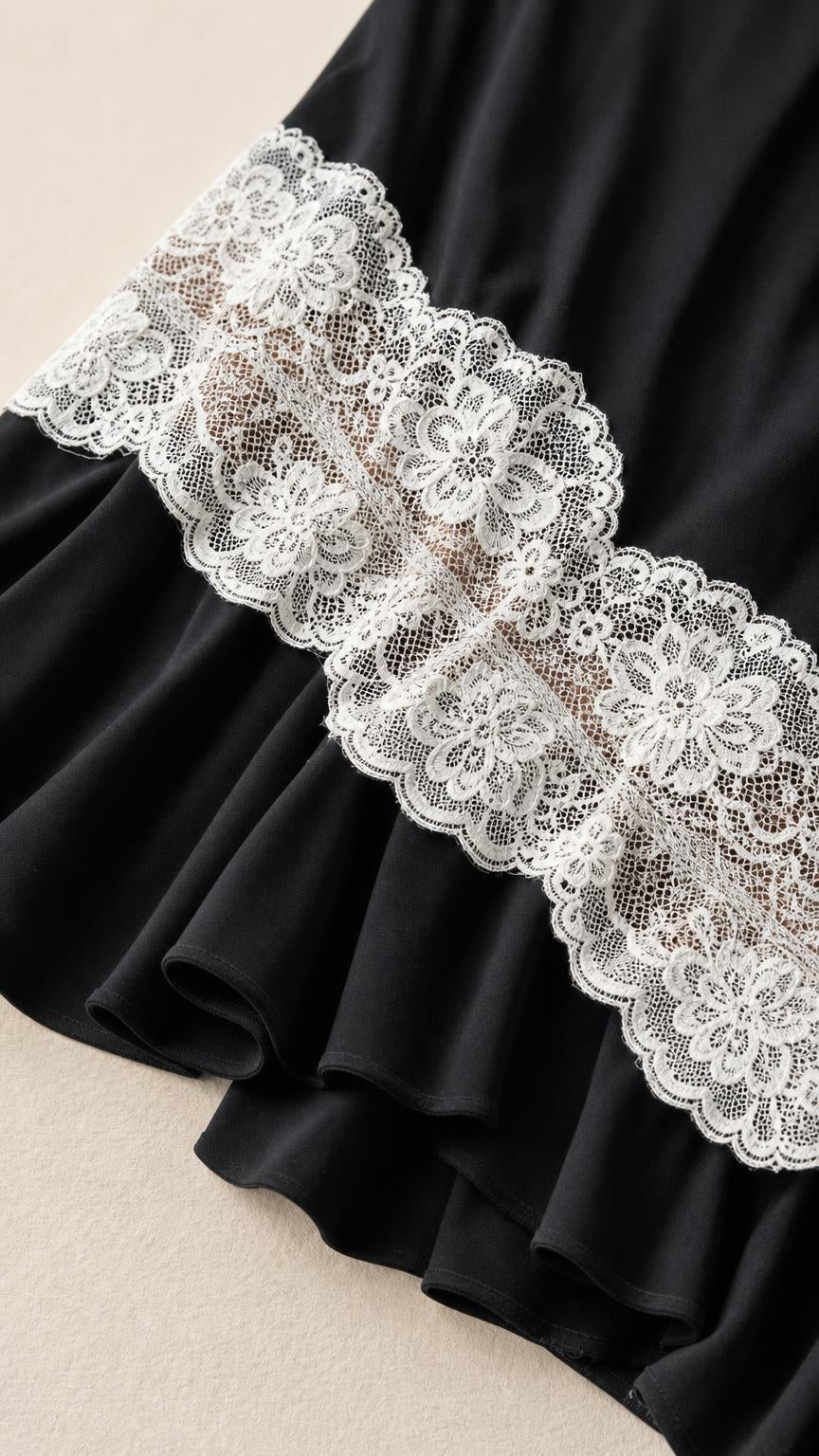 Close-up detail of the cream floral lace trim and black ruffled hem
