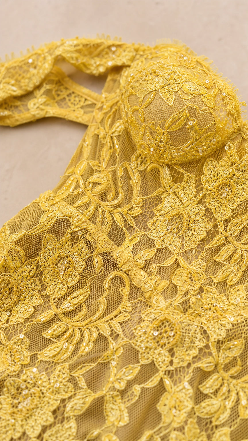 Close-up detail of yellow floral lace fabric and bodice