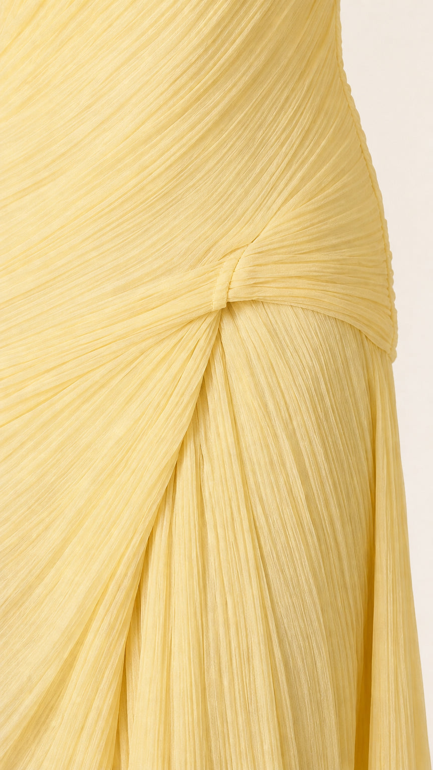 Close-up detail of pleated texture and side knot on yellow maxi dress
