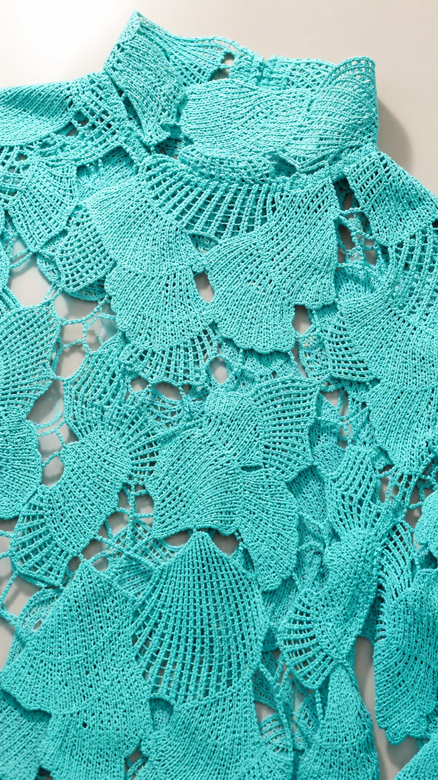 Close-up detail of turquoise floral crochet fabric and high neckline