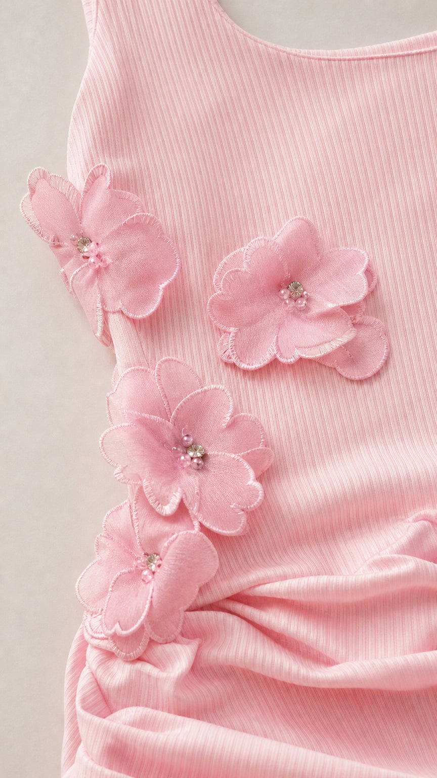 Close-up of 3D floral appliqués and ruching on pink mini dress