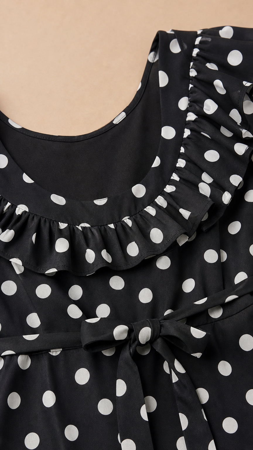 Close-up of ruffled neckline and tie waist on black polka dot dress