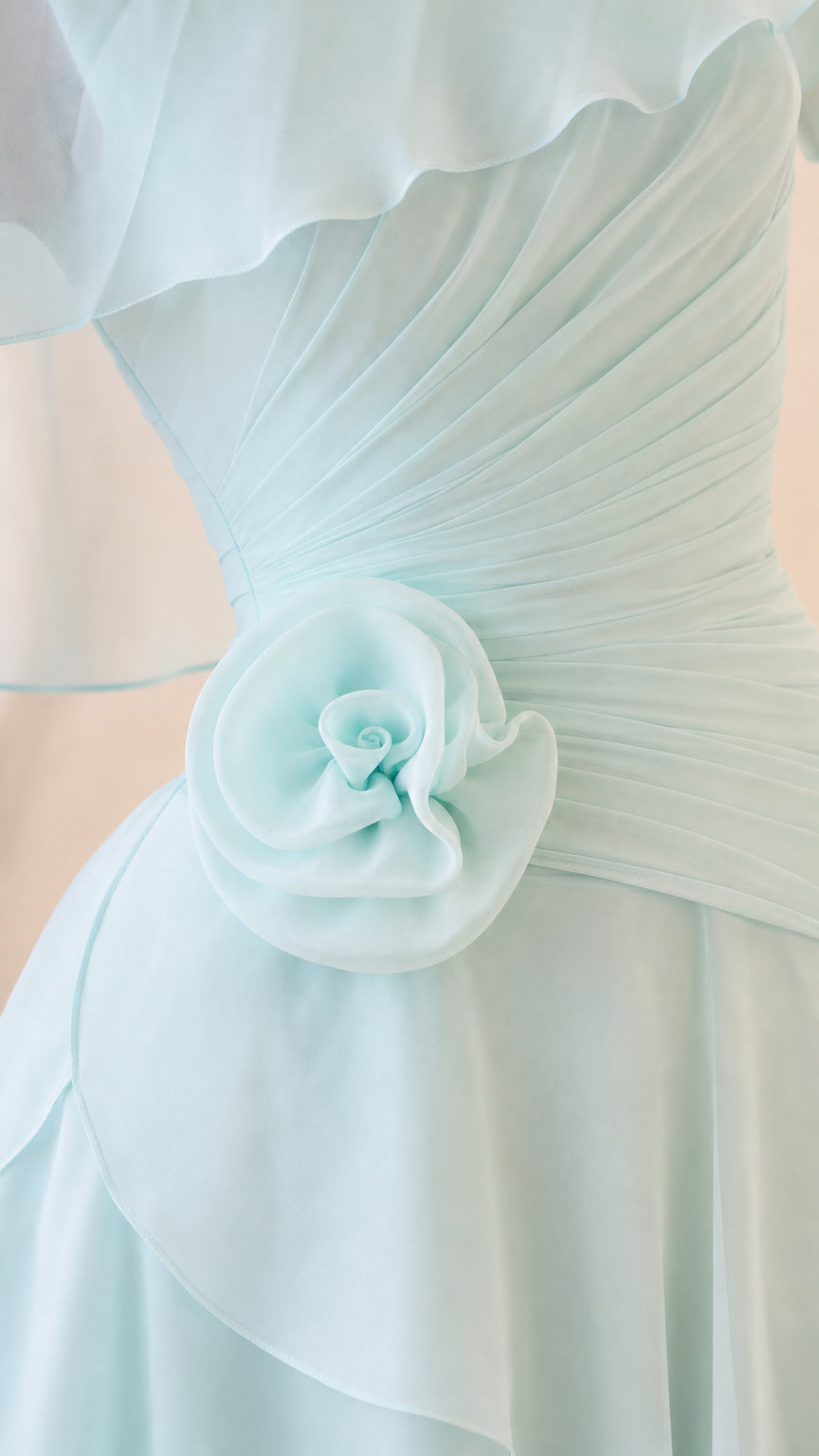 Close-up of pleated waist and floral applique on light blue dress