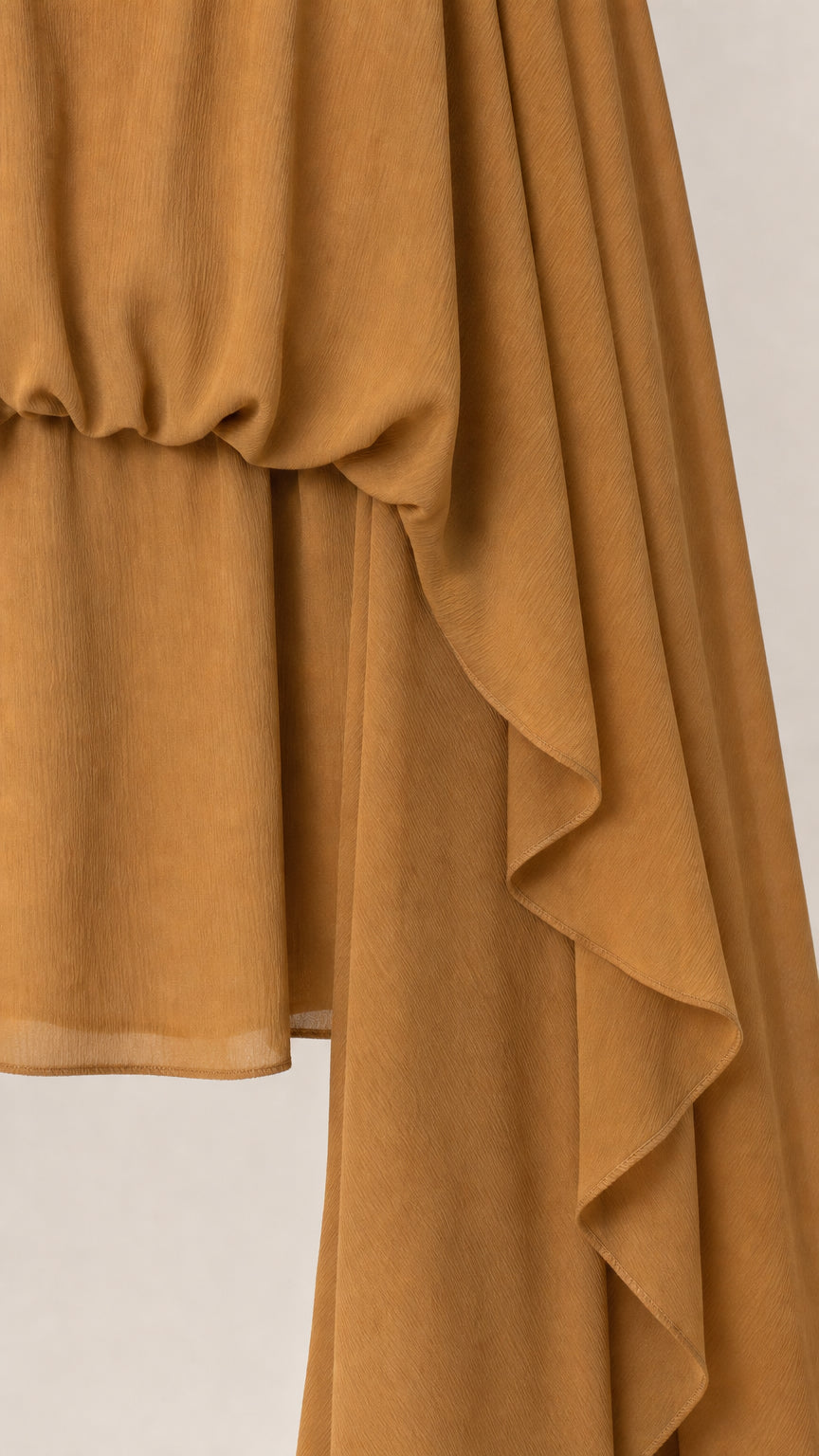 Close-up detail of smooth fabric and hemline on camel dress