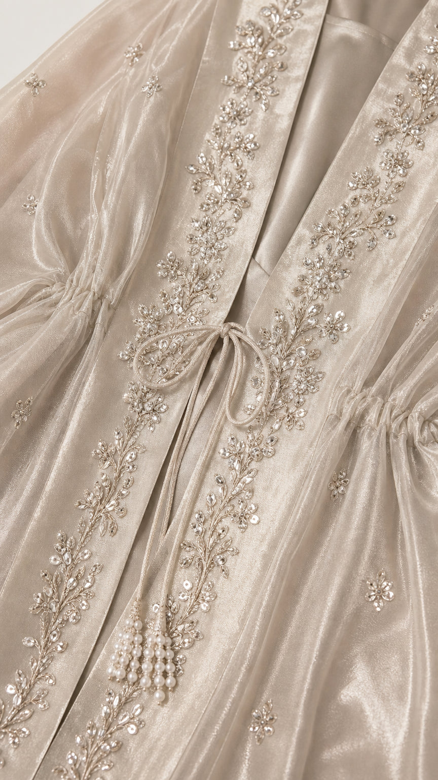 Close-up detail of front tie closure and intricate silver embroidery