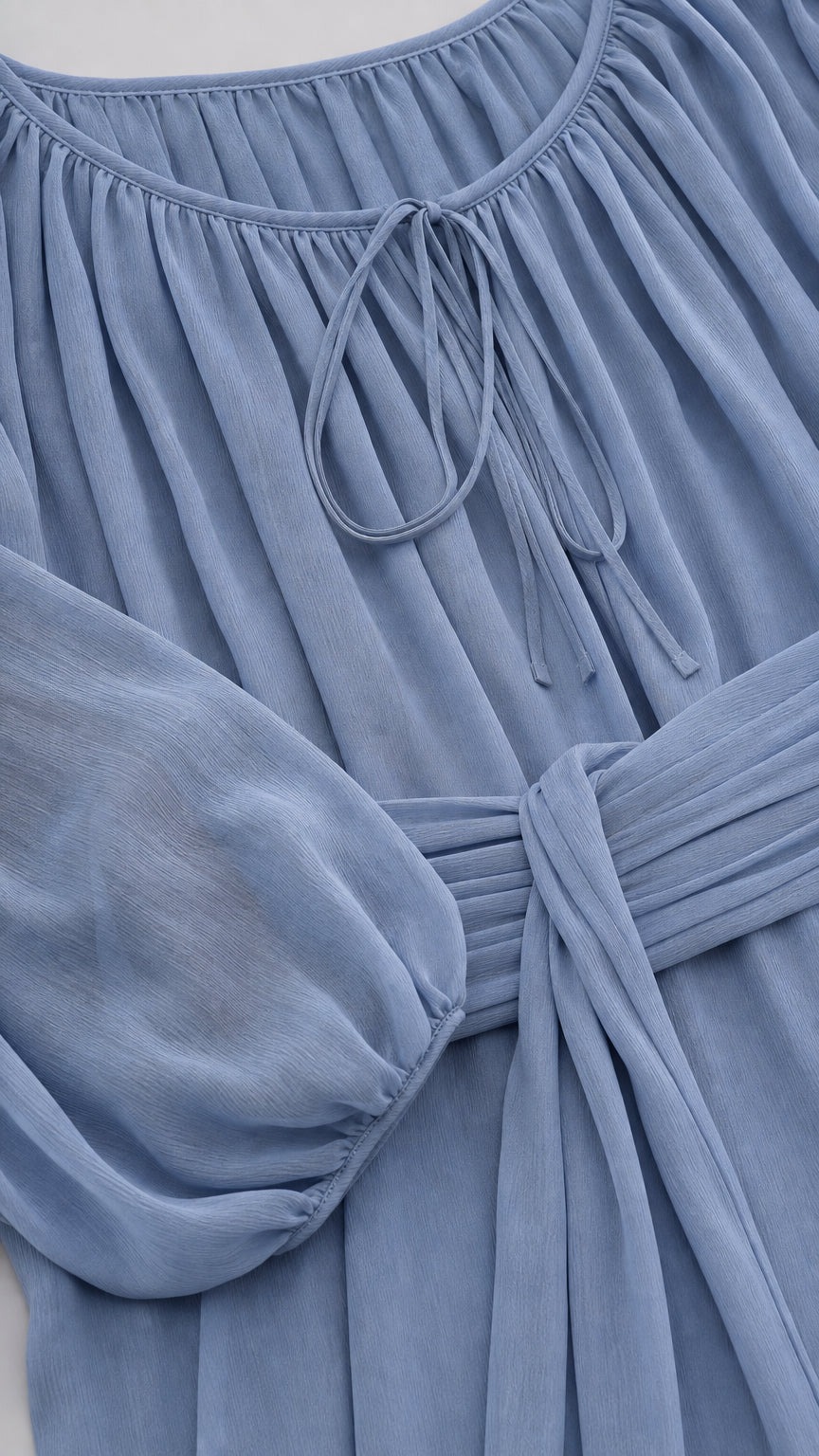 Close-up detail of neckline and pleated waist tie on blue midi dress