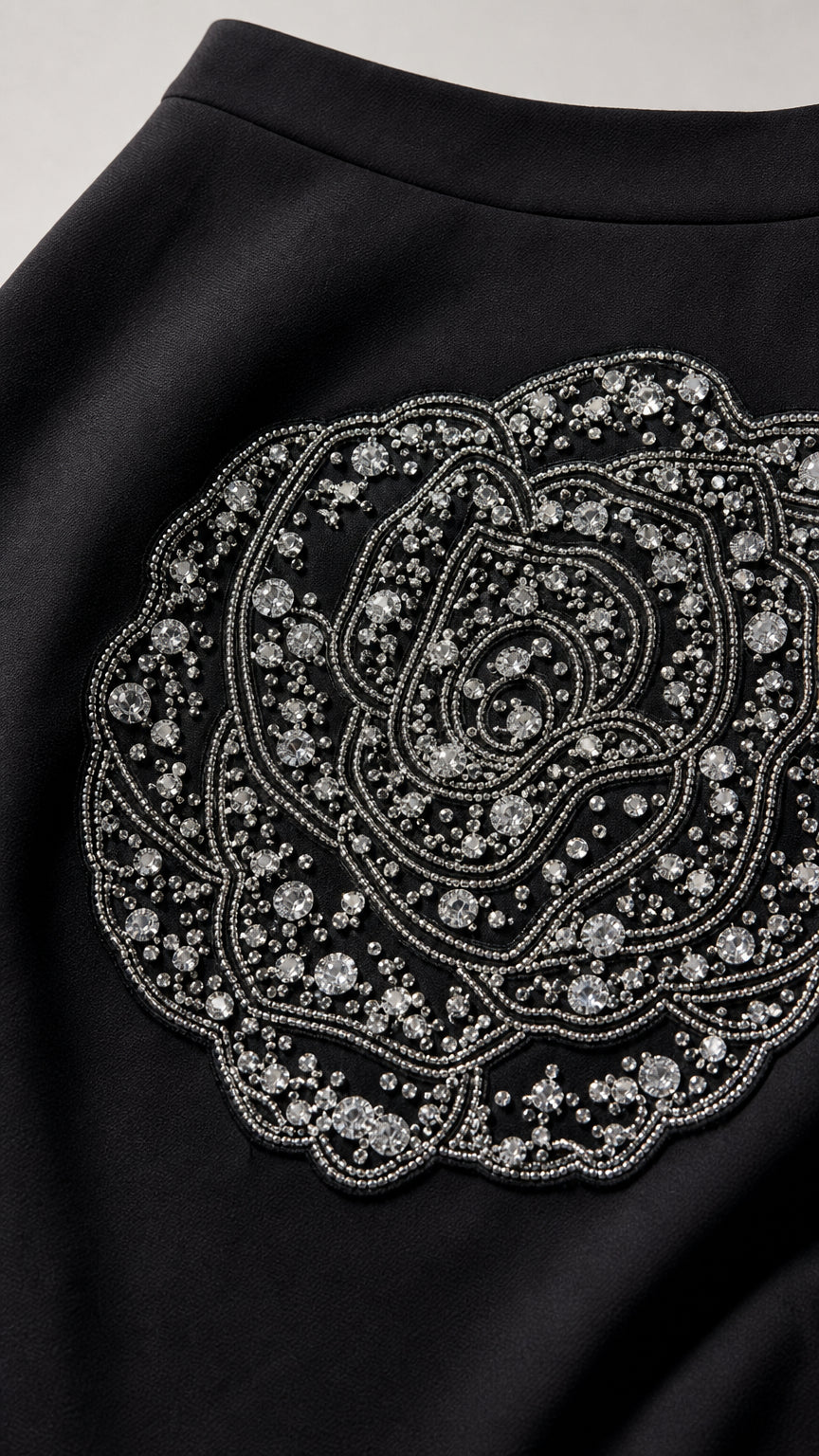 Close-up of intricate rhinestone and bead rose applique on black skirt