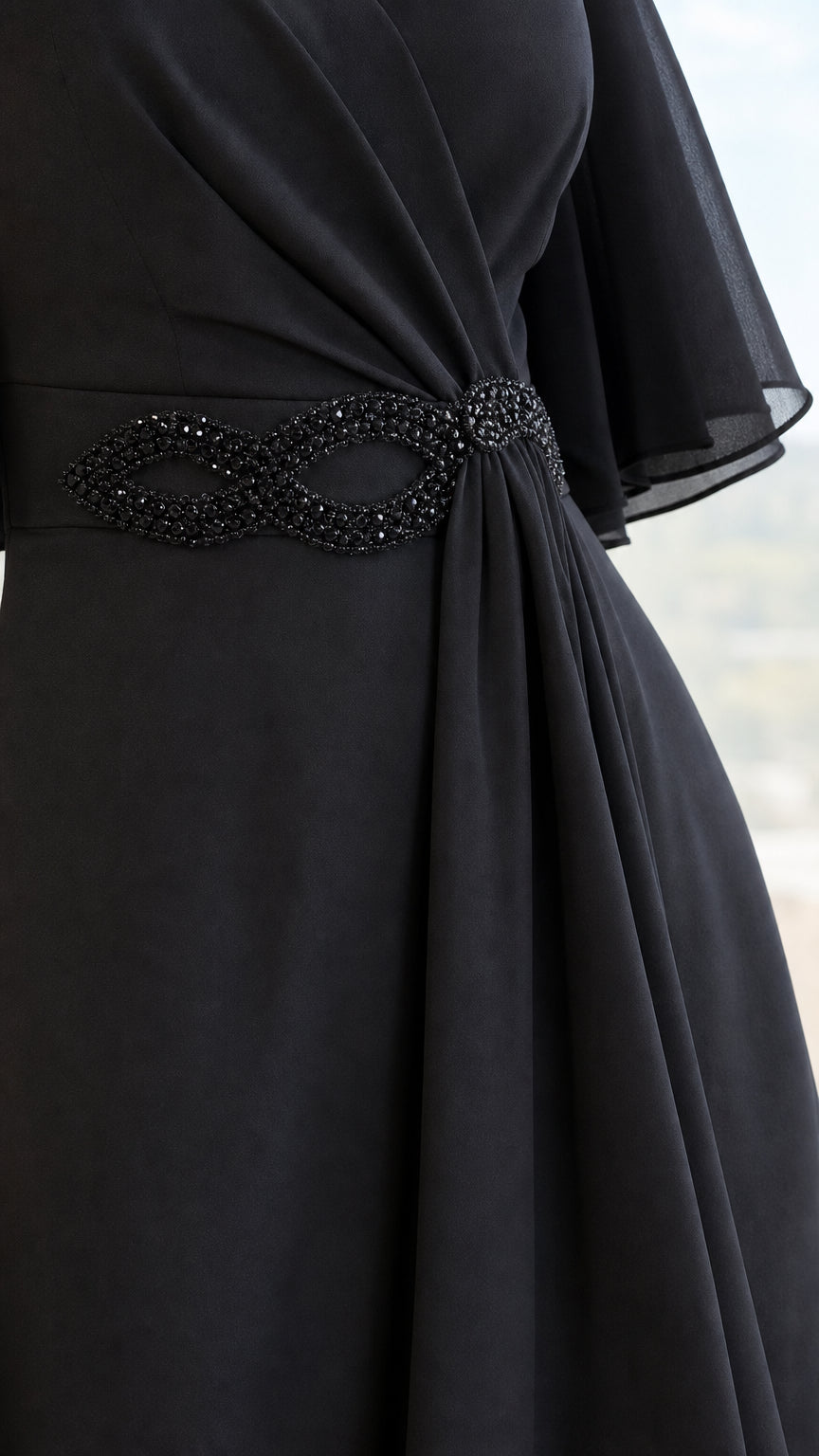 Close-up of embellished crystal waist detail on black chiffon dress