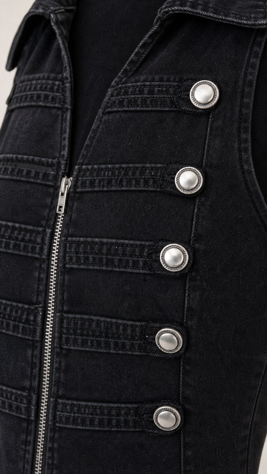 Close-up detail of silver buttons and zipper on black denim vest