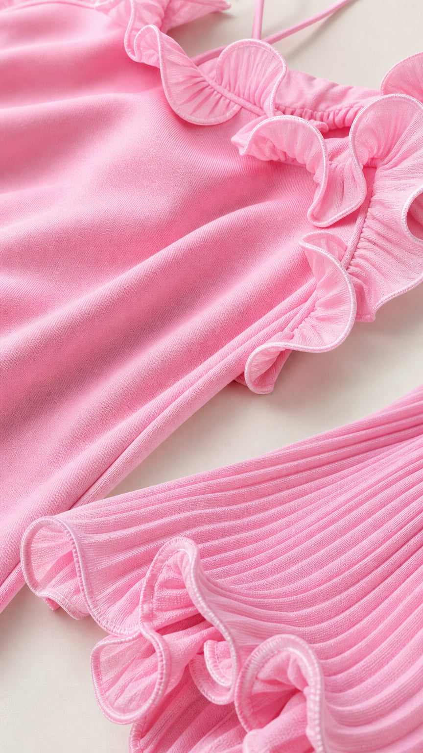Close-up detail of fabric, neckline ruffles, and pleated hem